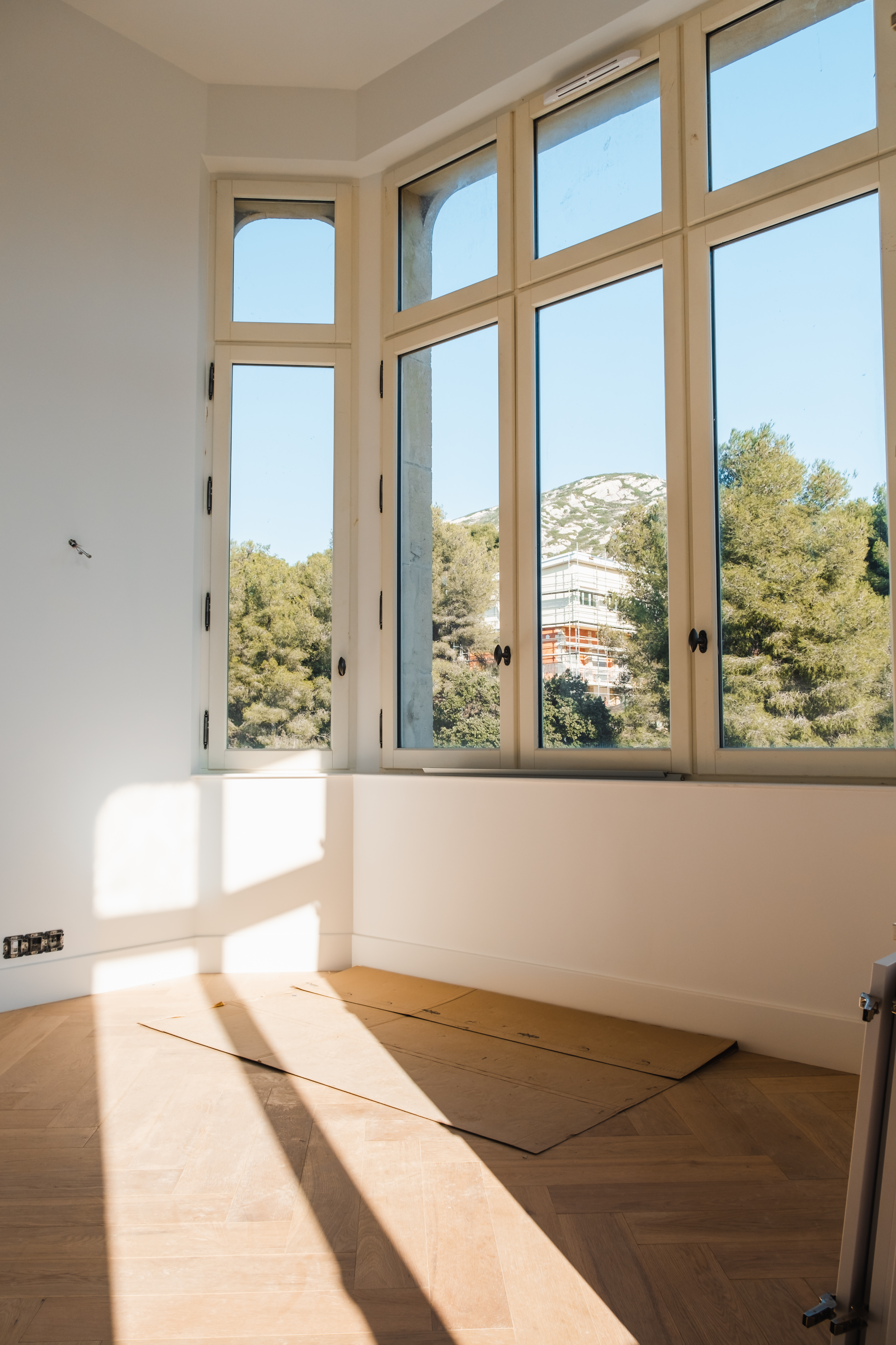 Belmont rénovation — chambre lumineuse avec fenêtres arquées et parquet chêne